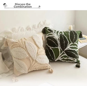 Close-up of tufted leaf pattern and tassels on beige and olive green cushion covers
