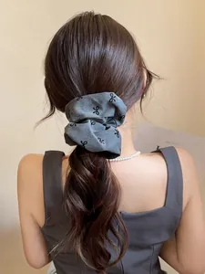Dettaglio dell'elastico scrunchie grigio in tessuto con fiocchi per coda bassa