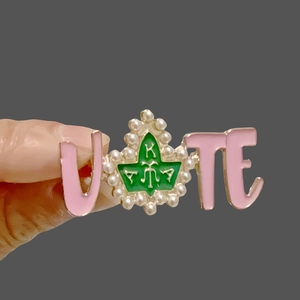 Pink VOTE brooch with green ivy leaf AKA letters and faux pearls held in hand