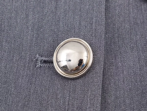Vue détaillée d'un bouton métallique argenté sur le tissu en sergé gris d'un costume
