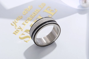 Detail of wide stainless steel ring with brushed texture and black enamel groove center