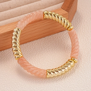 Détail du bracelet géométrique épissé en métal doré torsadé et résine acrylique rose
