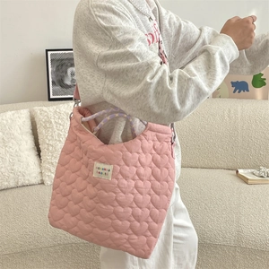 Détail du sac matelassé rose à cœurs avec bandoulière tissée et étiquette blanche