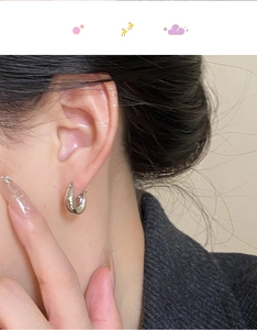 Close-up of modern minimalist wide teardrop silver earrings worn by a model
