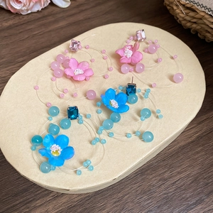 Detailed shot of pink and blue fabric flower earrings with beads and square gemstones