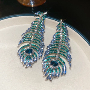 Macro detail of luxury feather drop earrings with blue rhinestones and silver base