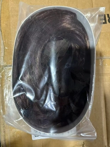 Detail view of deep brown long wavy synthetic hair wig packed in a transparent plastic bag
