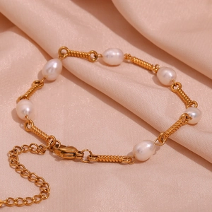 Detail of 18K gold-plated bracelet with freshwater pearls on pink satin background