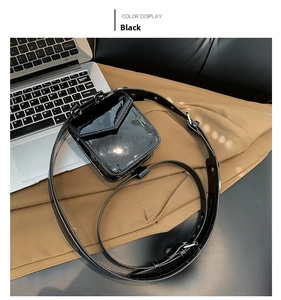Top view of shiny black mini square waist bag with adjustable strap on a lifestyle desk