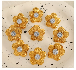 Close-up of golden floral stud earrings with rhinestones on a ceramic tray