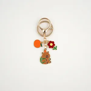 Detail of alloy Capybara keychain with orange persimmon and cute backpack bear charms
