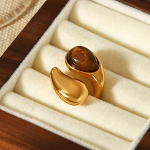 Détail d'une bague goutte en oeil de tigre doré sur un support en velours doux