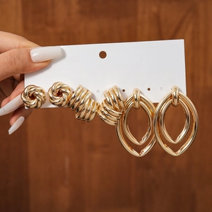 Detailed view of three pairs of textured gold metal earrings on a white display card