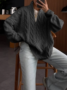 Detail of dark grey cable knit sweater featuring a half-zip high neck and ribbed texture
