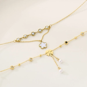 Golden clover charm jewelry set with necklace, bracelet, and pearls on beige background