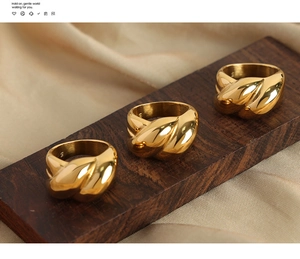 Dettaglio macro di anelli a corda intrecciata placcati in oro su espositore in legno