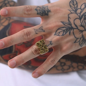 Macro shot of gold vintage steel ring featuring FUCK OFF engraving on model's hand