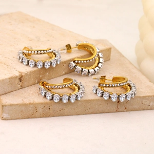 Detail of gold double-layer earrings with pearls and zircon crystals on a stone base