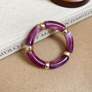 Detail view of purple marble resin segments joined by polished gold metal ring buckles