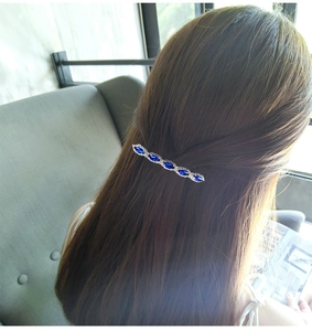 Close-up of vintage metal hair clip with blue marquise crystals on brown hair