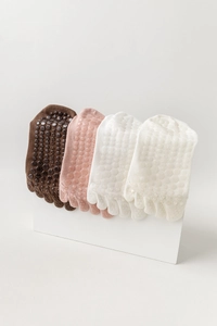 Detail of non-slip grips on four pairs of colorful cotton yoga five-toe socks