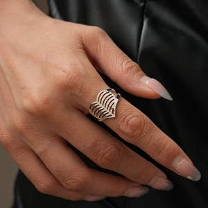 Close-up of silver heart-shaped hollow ring with leaf vein texture on leather background