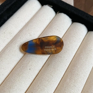 Gros plan d'une pince à cheveux en acrylique faite main avec motif écaille et logo
