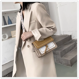 Detail of color-block crossbody bag featuring gold hardware and patterned wide strap