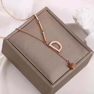 Macro detail of 18K gold titanium necklace with D letter pendant on display stand