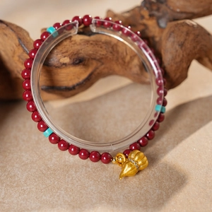 Detailed shot of cinnabar bead bracelet with blue spacer and golden gourd pendant