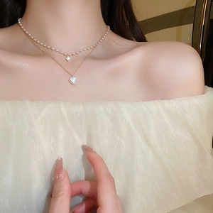 Détail d'un élégant collier doré double épaisseur avec perles et pendentifs cœur