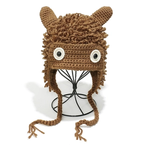 Macro shot of brown hand-crocheted cartoon animal hat with loop pile texture and 3D ears