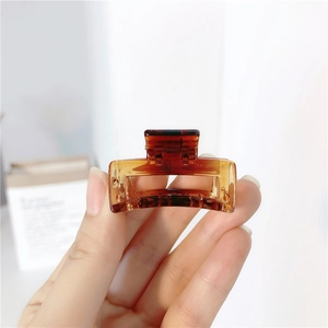 Detail of amber translucent square hair claw clip with metallic spring and resin finish