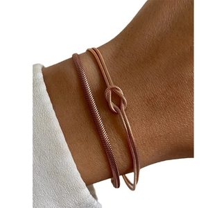 Rose gold snake chain bracelet featuring a unique knot design worn on a wrist