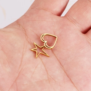 Polished gold stainless steel hollow heart and star charms held in hand for DIY jewelry