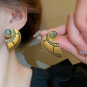 Macro detail of vintage matte gold fan-shaped earrings with grey-blue crystal stones
