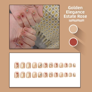 Close-up of nude pink press-on nails with red rose patterns and golden glitter accents