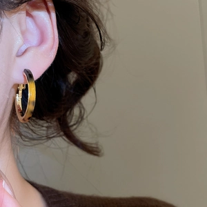 Close-up of leopard print resin and gold metal C-shaped hoop earring on model