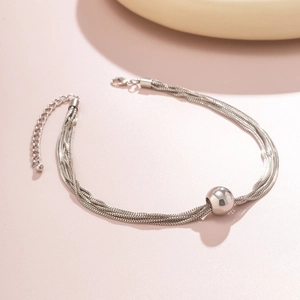 Detail of silver layered chain bracelet with a spherical bead and lobster clasp