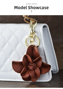 Close-up of brown leather flower charm with gold clasp on a white quilted handbag