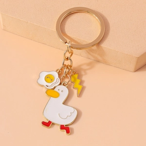Detail of cute white enamel duck keychain with fried egg and lightning bolt charms
