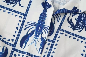 Macro detail of white shirt with blue lobster and crab prints showing fabric texture