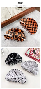 Detail shot of Halloween acrylic claw clips with pumpkin, skull and spider web patterns