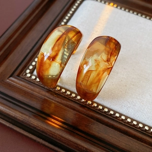 Macro shot of amber resin C-shaped hoop earrings with vintage tortoiseshell texture