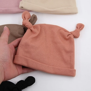 Gros plan d'un bonnet en tricot côtelé rose corail avec nœuds pour bébé