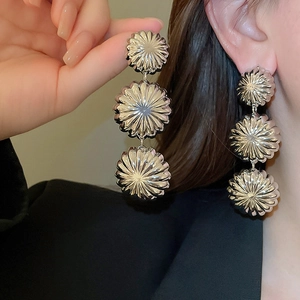 Detail of silver triple-layered metal flower earrings with textured sunburst petals