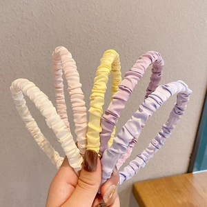 Minimalist pleated satin headbands in five pastel colors held for a group product view