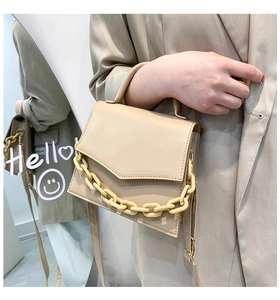 Detail of beige PU leather crossbody bag with decorative oversized chain and envelope flap