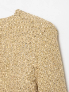 Close-up of gold tweed jacket fabric showing metallic threads and sequin details