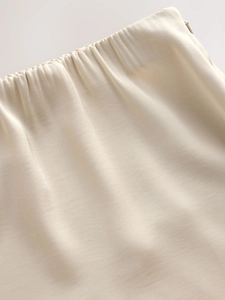 Detailed close-up of the beige satin skirt waist featuring elastic band and side zipper